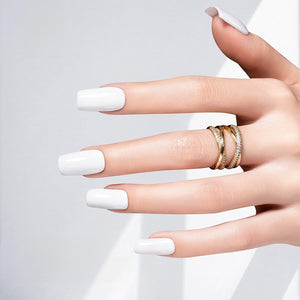 Beautiful hand with titanium white gel nail polish and stylish gold rings.