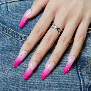 Fuchsia pink gel nail polish with rhinestones on long nails, stylish design on denim background.